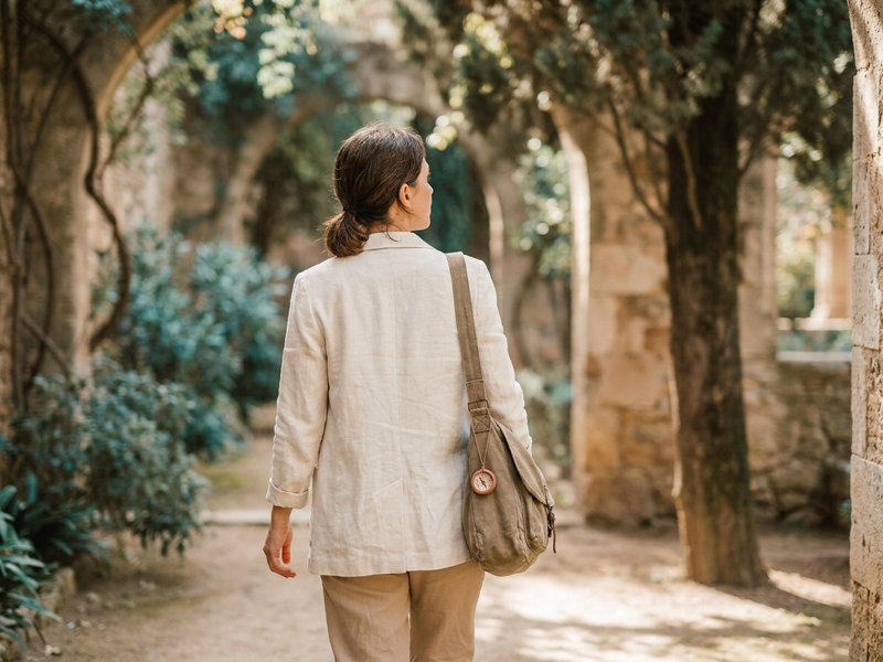 Woman on her first solo day trip walking through a historic site with a day-bag on her shoulder