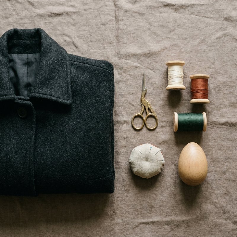 cheap hobbies, hands-free flat lay of mending thread, scissors and a folded wool coat, herowncompass.com